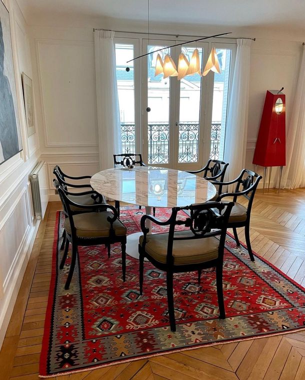 Red kilim with geometric motifs beneath a marble table, in a Parisian dining room