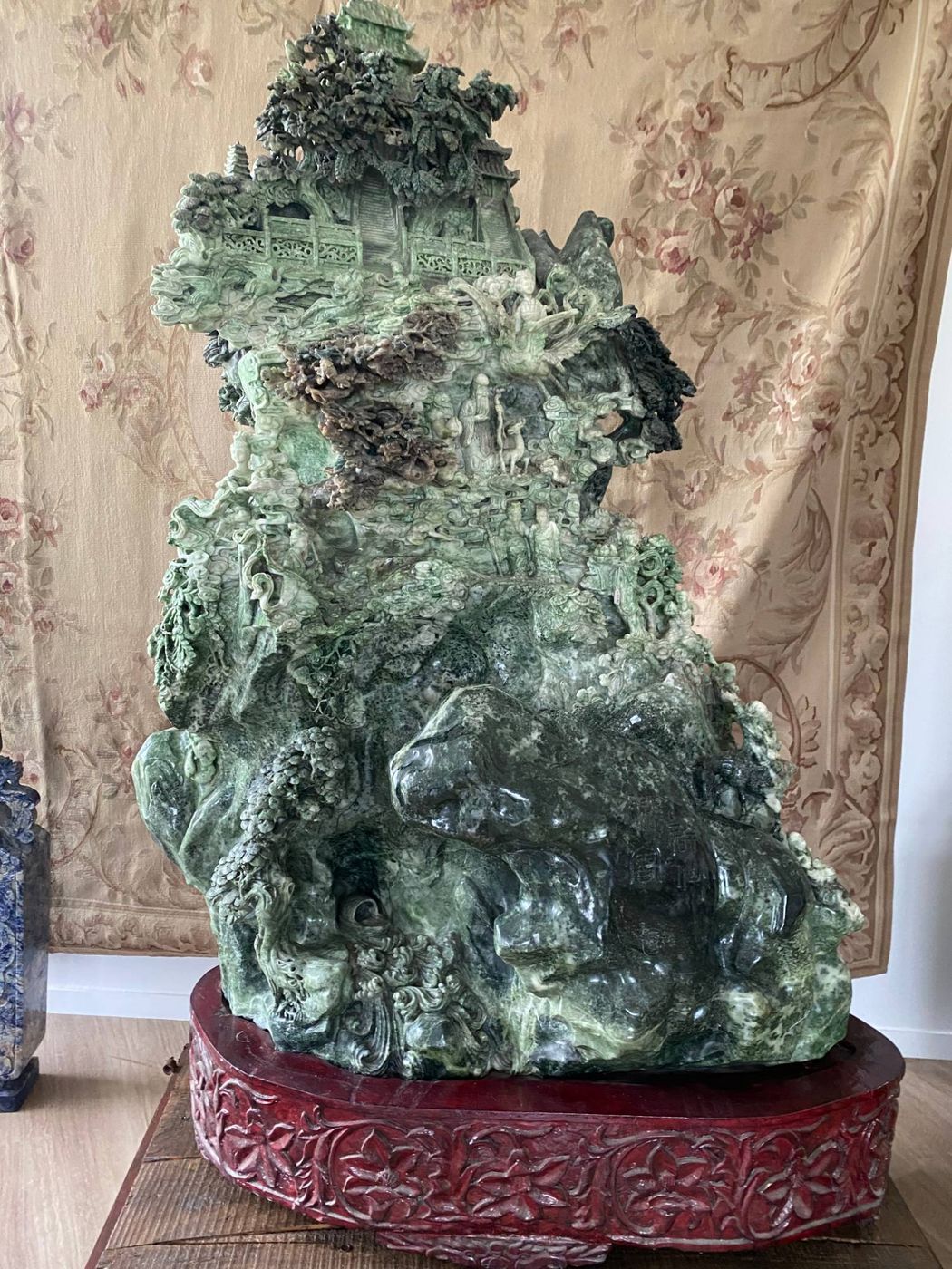Large Chinese sculpture in green hardstone: a mountain carved with pavilions, trees and figures, on a carved wooden stand