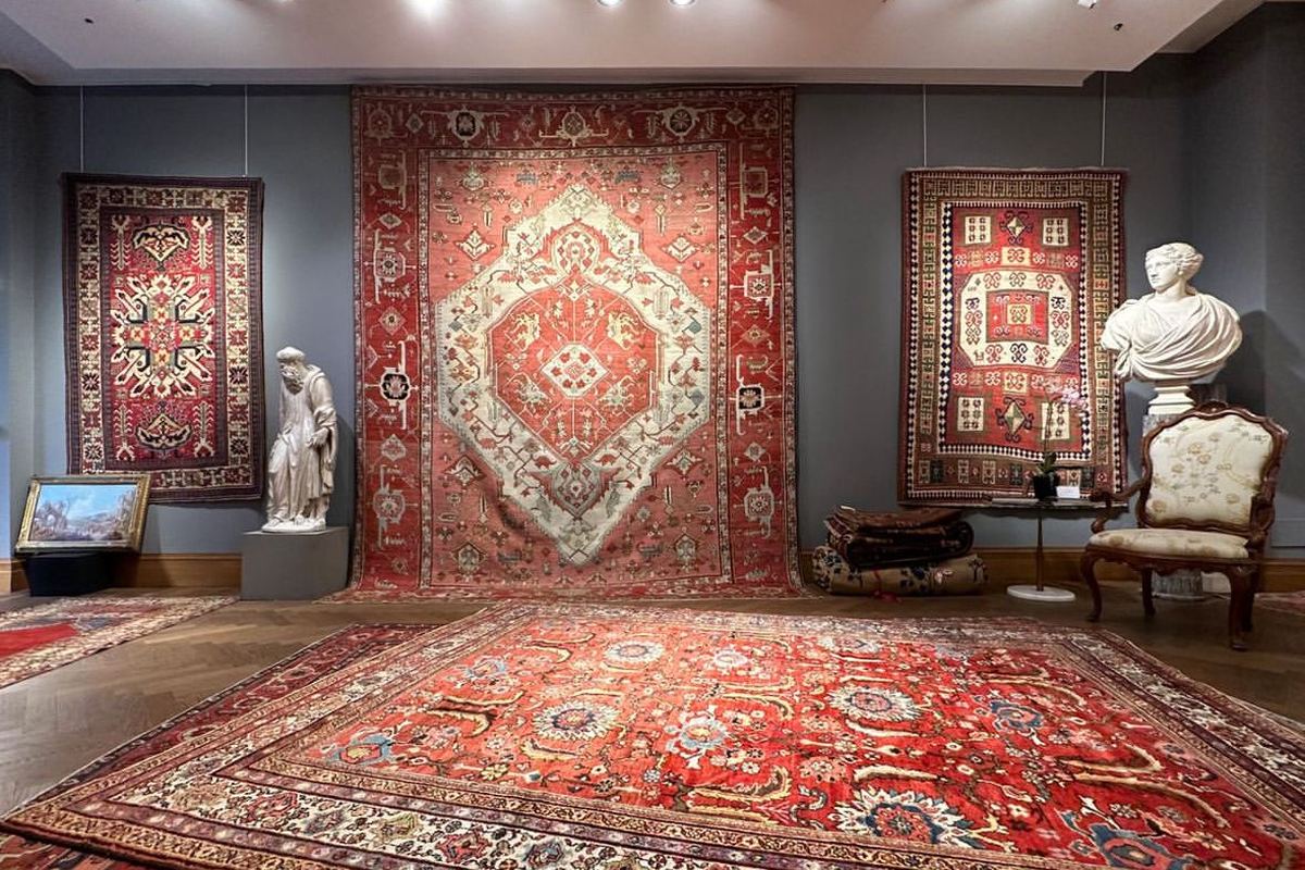 Antique Persian and Caucasian rugs hung on the walls and laid on the floor, with antique sculptures, a painting and an armchair