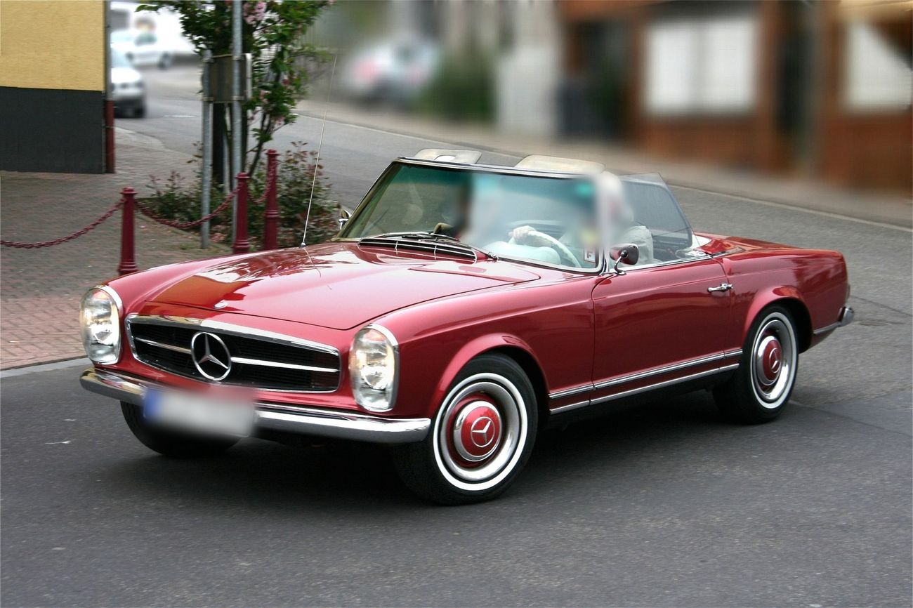 Red 1960s Mercedes-Benz convertible out on the road