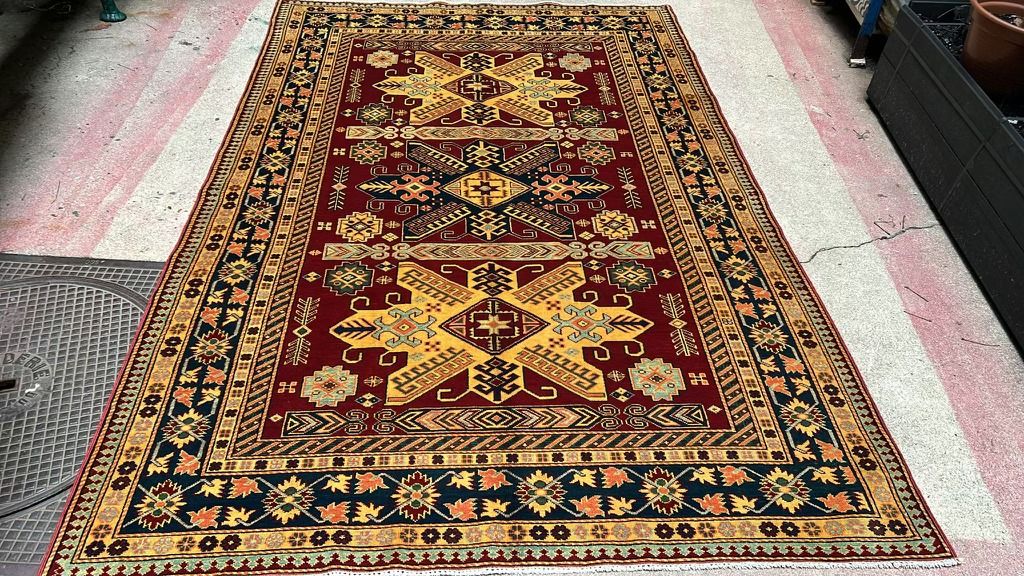 Hand-knotted Kazak rug: large yellow star medallions on a red field, midnight-blue border