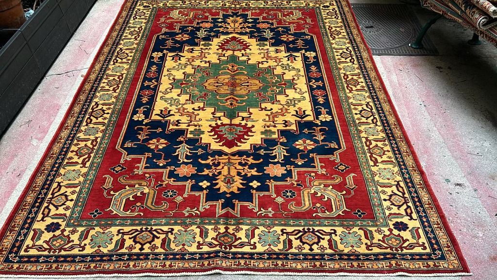Hand-knotted Kazak rug with a green and gold central medallion on a midnight-blue ground, red field and border